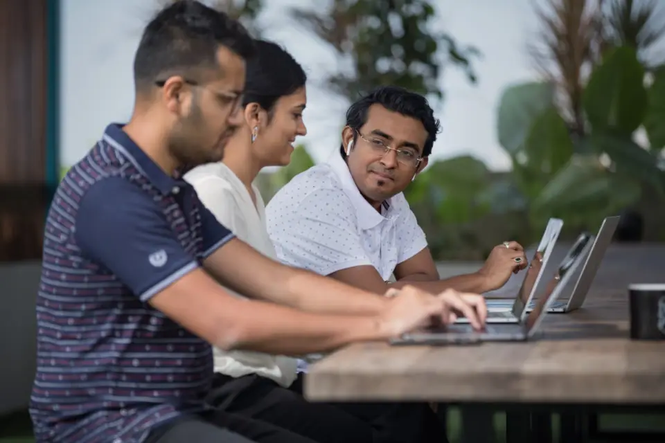 Três colegas trabalhando juntos em notebooks